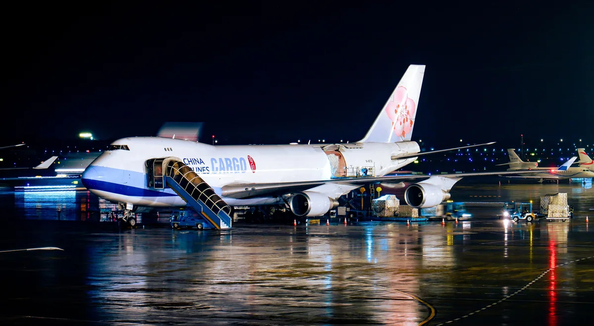 Cargo aircraft with its main freight door open during nighttime ground operations